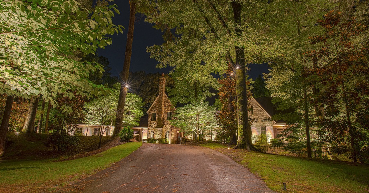 View of house with landscape lighting from driveway
