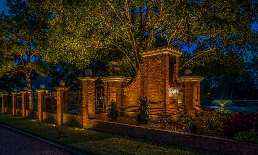 Commercial landscape lighting neighborhood entrance brick fence uplighting