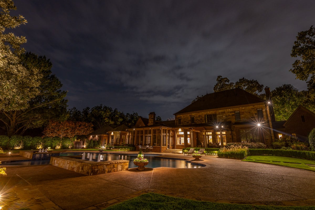 backyard and pool and house with custom landscape lighting