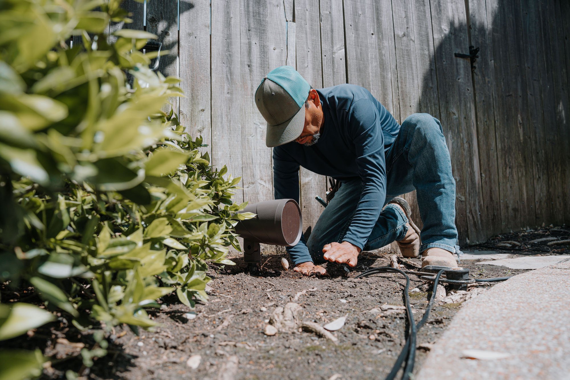 Outdoor audio speaker in landscape technician installation wires